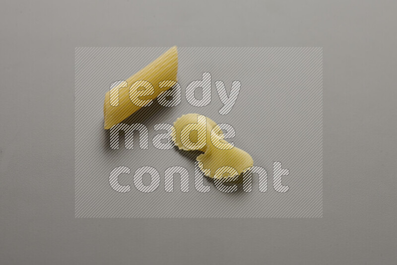 Penne pasta with other types of pasta on grey background