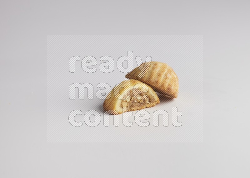 Two Pieces of Maamoul filled with walnut paste  one of them is cut direct on white background