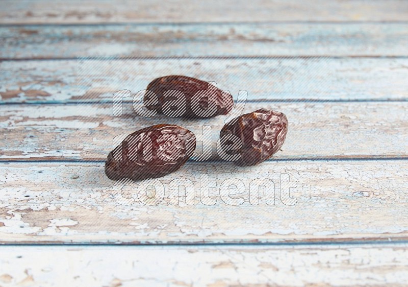 three madjoul dates on a light blue wooden background