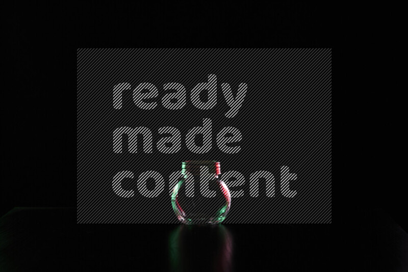 Glassware with rim light in red and green against black background