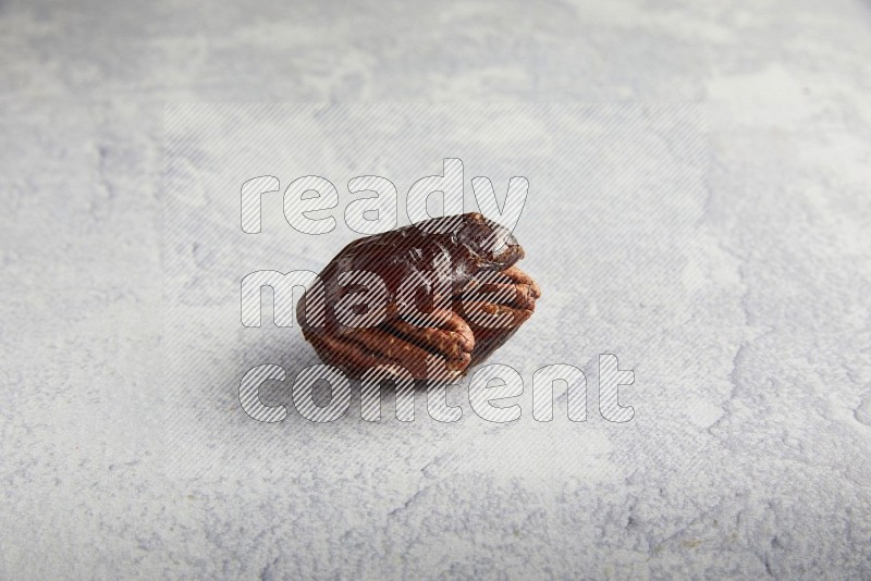 pecan stuffed madjoul date on a light grey background