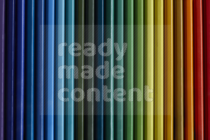 مجموعة من أقلام الرصاص الملونة مرتبة لتعرض تدرجا من الألوان المختلفة علي خلفية رمادية