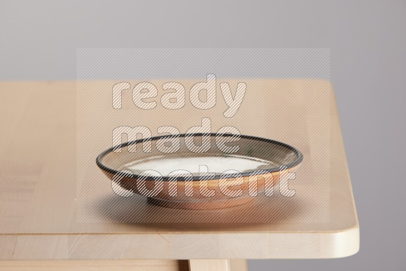 multi-colored pottery Plate on a wooden table edge