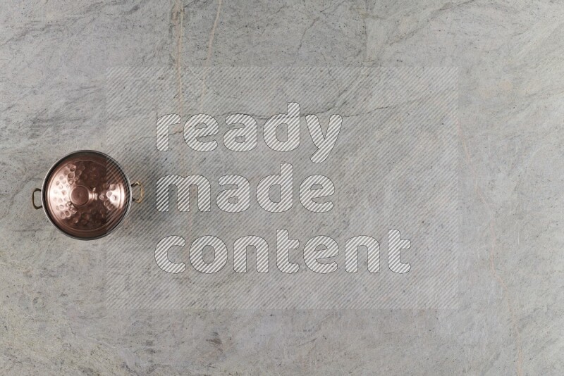 A small copper pot on grey marble background