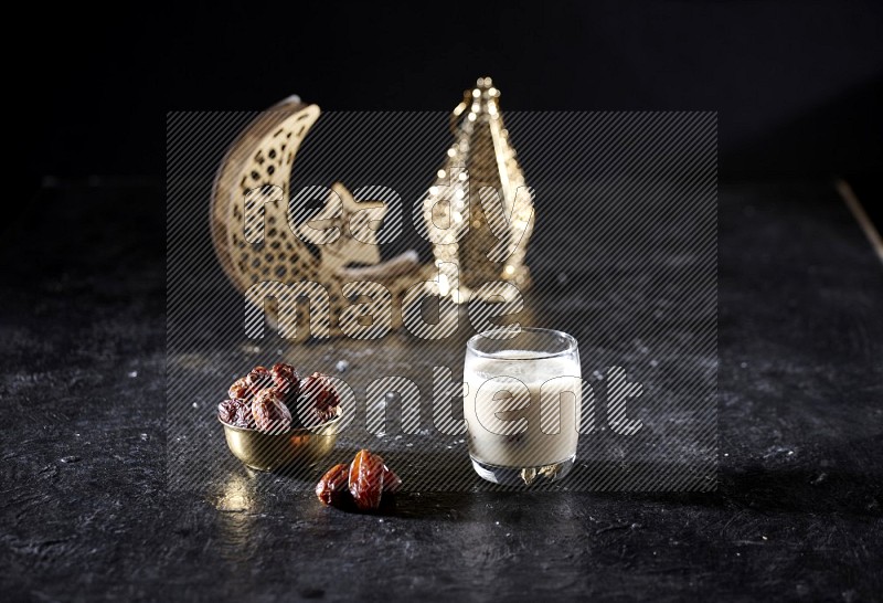 Dates in a metal bowl with dates smoothie beside golden lanterns in a dark setup