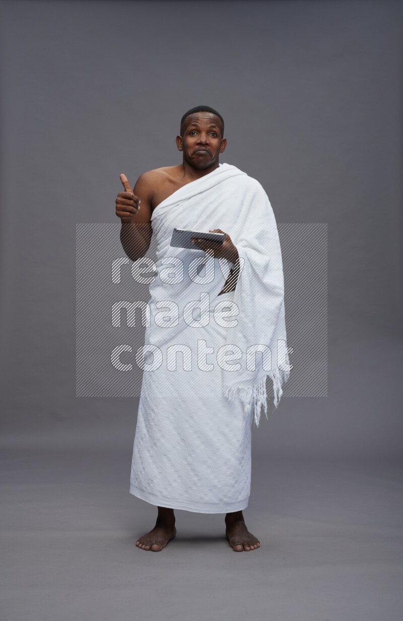 A man wearing Ehram Standing working on tablet on gray background