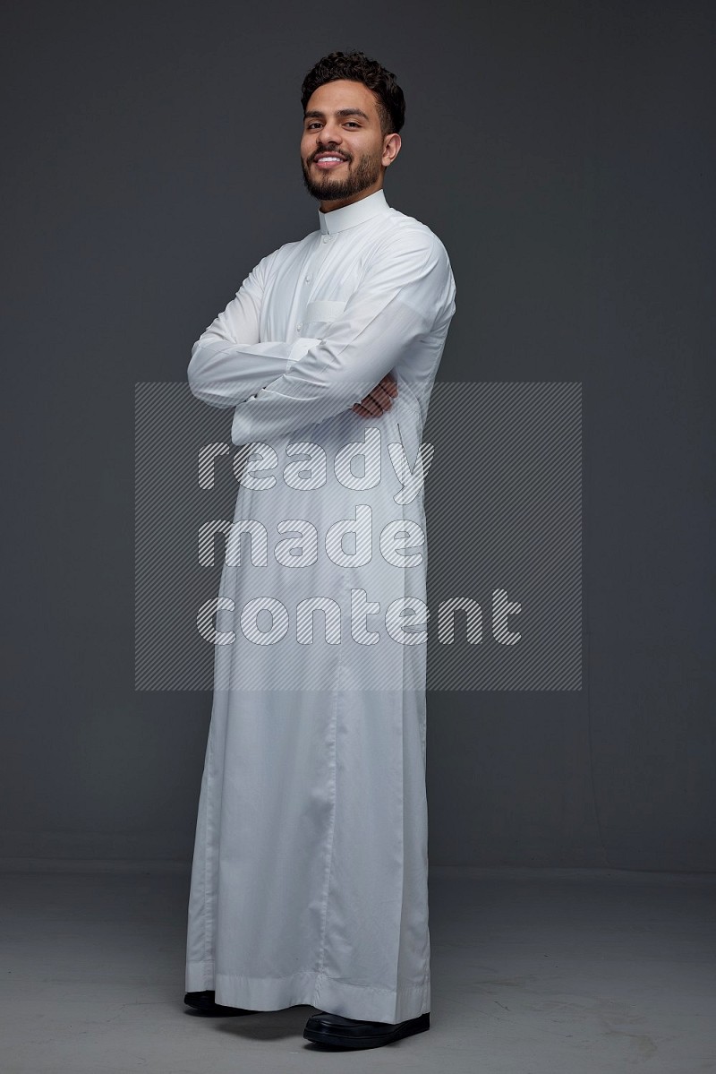 A Saudi man wearing Thobe standing and making different poses eye level on a gray background