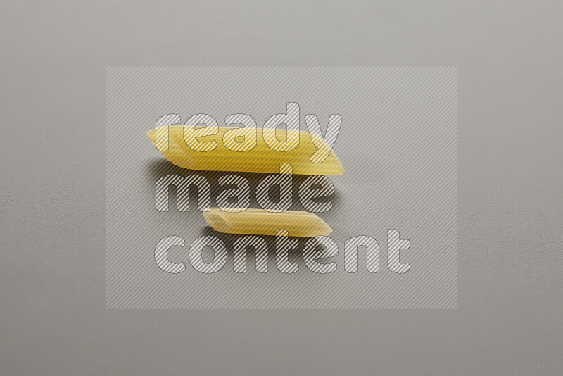 Penne pasta with other types of pasta on grey background