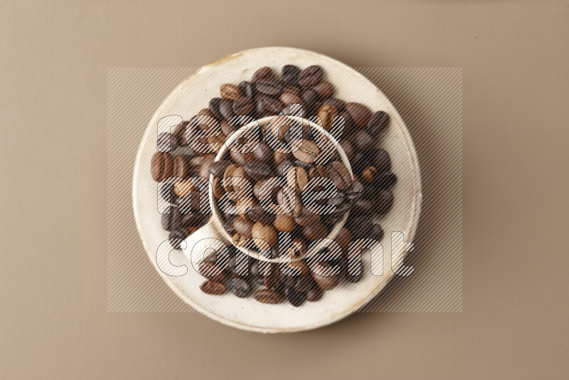 A beige pottery cup full of roasted coffee beans on beige background