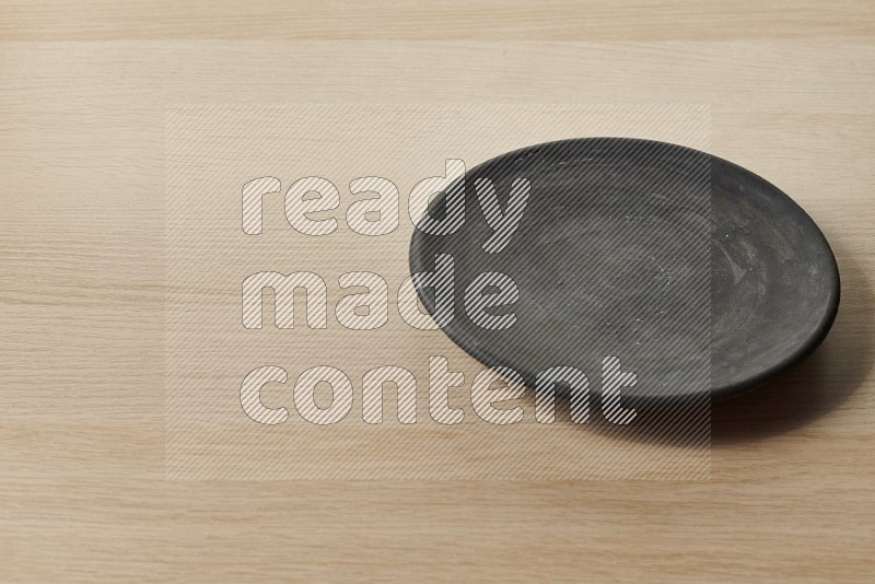 Black Pottery Plate on Oak Wooden Flooring, 45 degrees