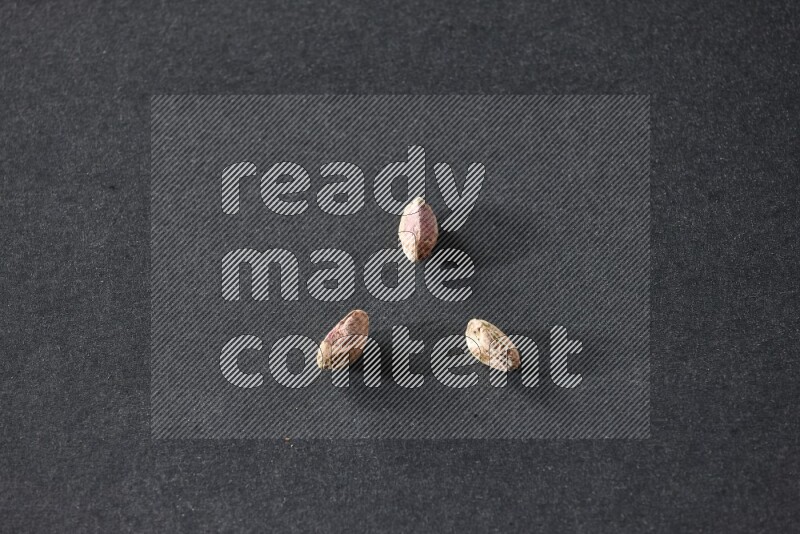 3 peeled pistachios on a black background in different angles