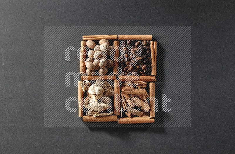 4 squares of cinnamon sticks full of coffee beans, cinnamon, dried ginger and nutmegs on black flooring
