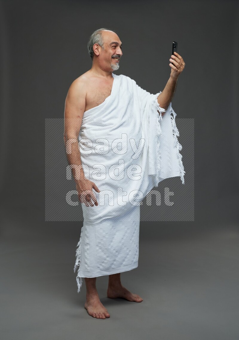 A man wearing Ehram Standing taking selfie on gray background