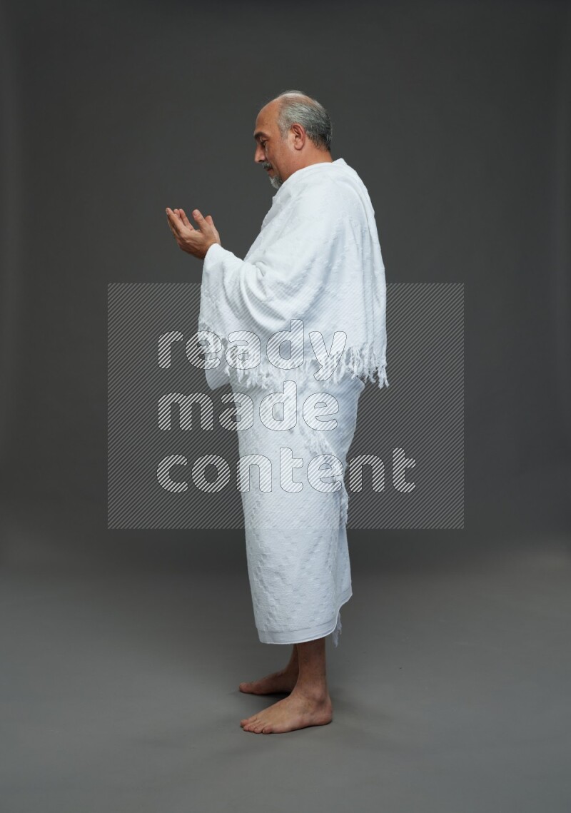 A man wearing Ehram Standing dua'a on gray background