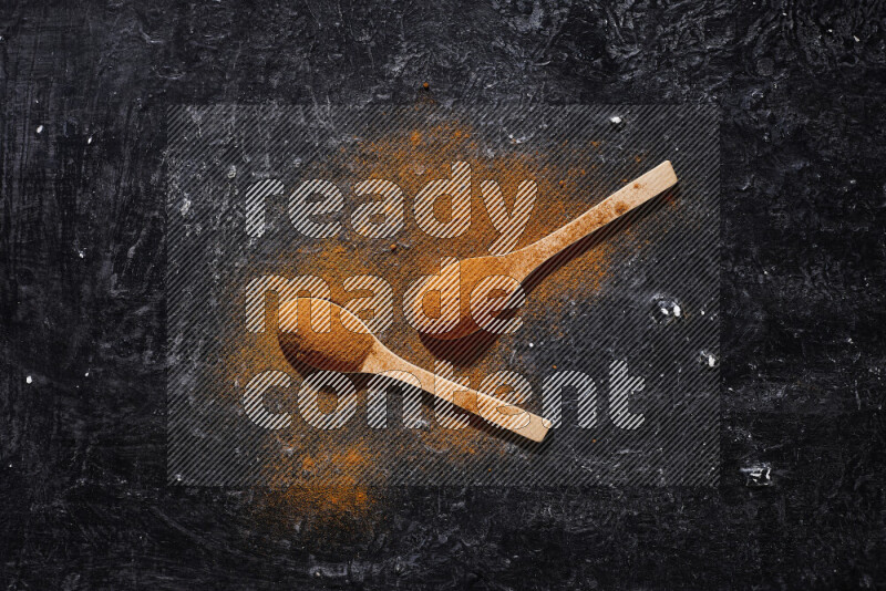 Two wooden spoons full of ground paprika powder on black background