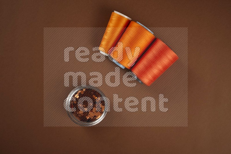 Orange sewing supplies on brown background