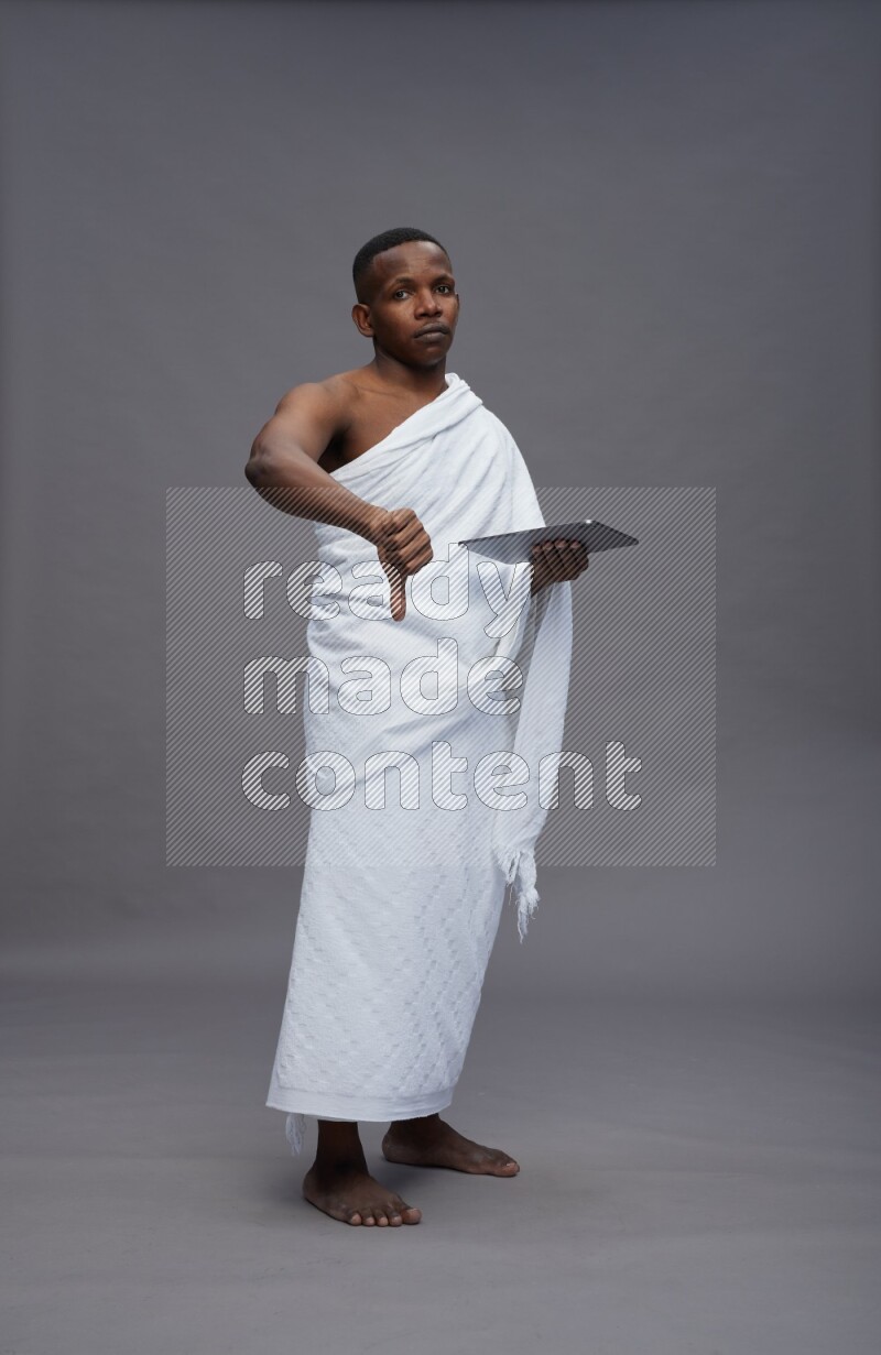A man wearing Ehram Standing working on tablet on gray background