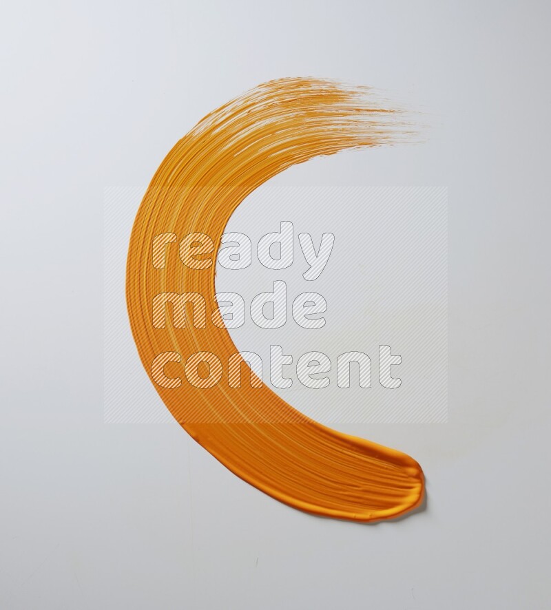 An orange half circular painting brush stroke on white background