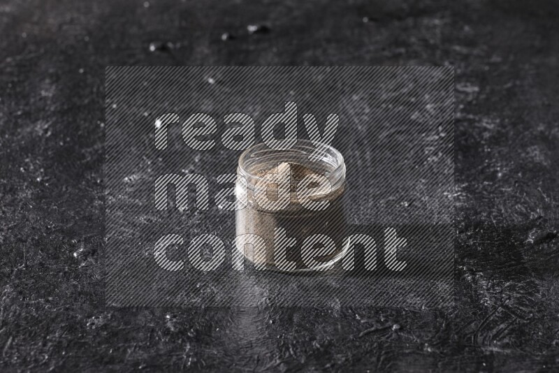 بودرة الفلفل الأسود في وعاء زجاجي علي خلفية سوداء