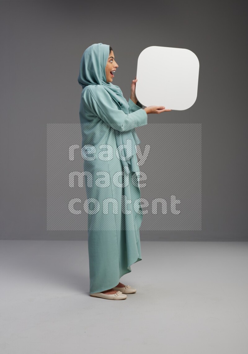 Saudi Woman wearing Abaya standing holding social media sign on Gray background