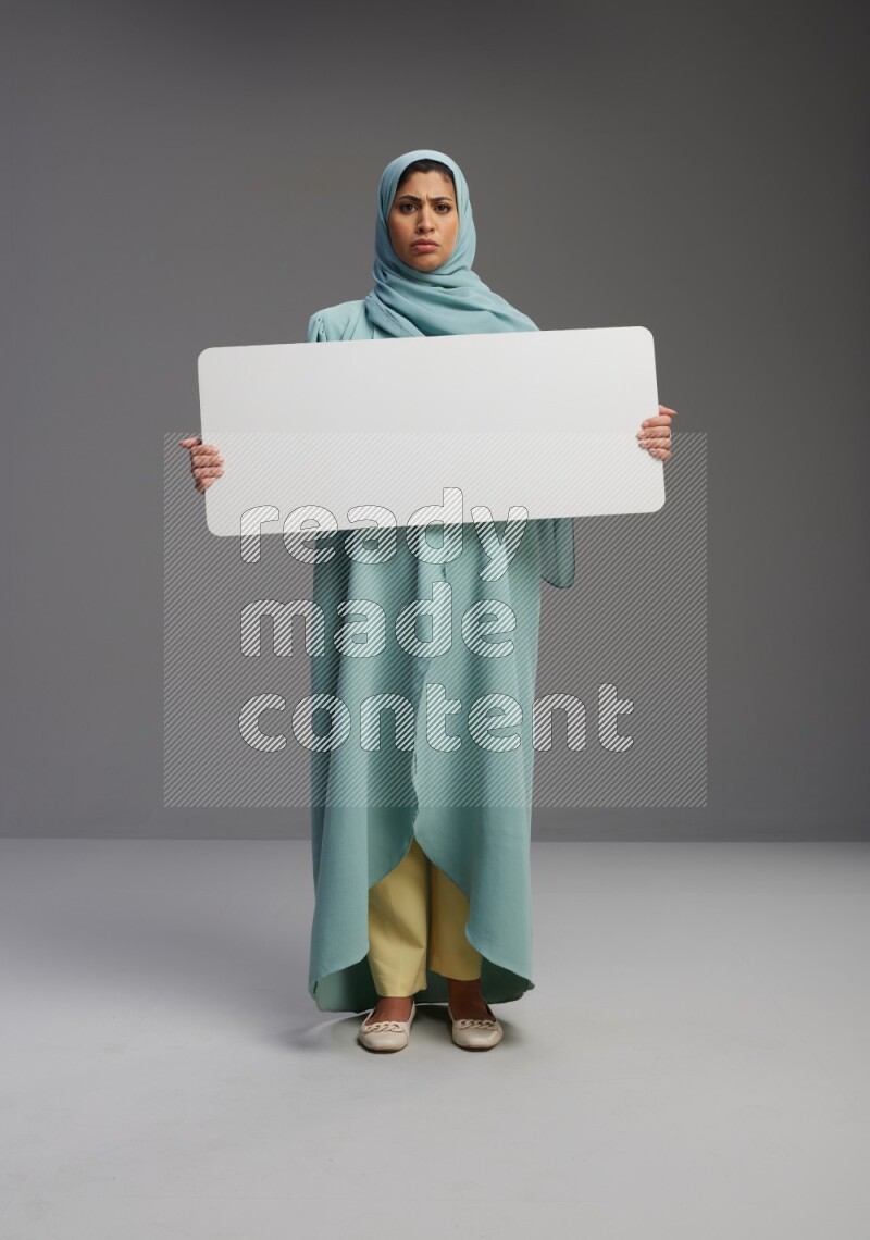 Saudi Woman wearing Abaya standing holding board on Gray background