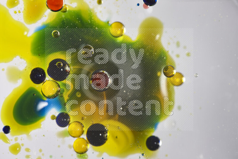 Close-ups of abstract red, blue, yellow and green watercolor drops on oil Surface on white background