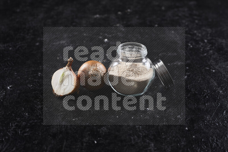 A glass jar full of onion powder on black background