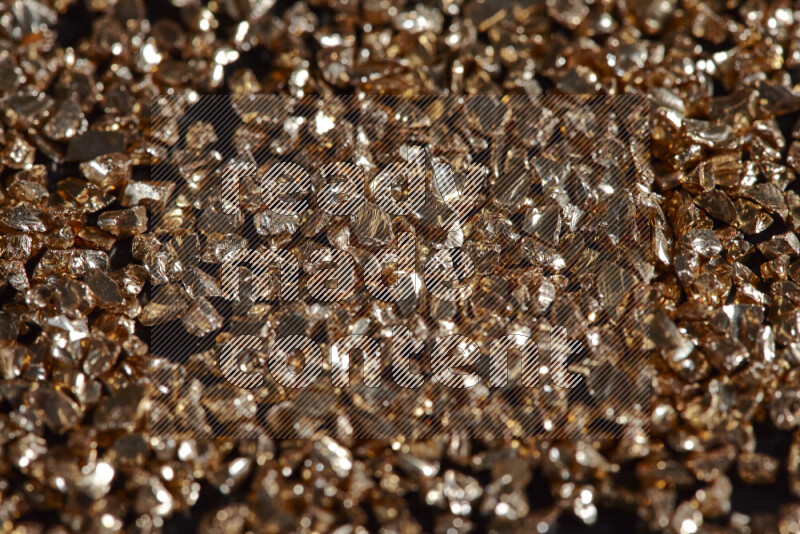 Gold shimmering fragments of glass scattered on a black background