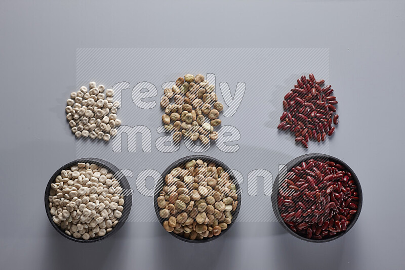 Legumes in pottery bowls on light grey background