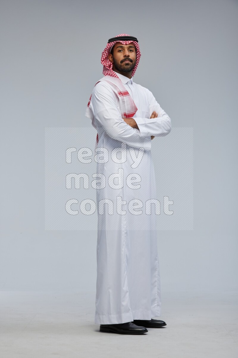 Saudi man Wearing Thob and shomag standing with crossed arms on Gray background