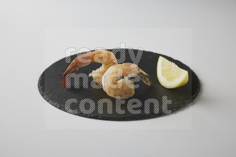 two grilled shrimp  on a black slate direct  on a white back ground