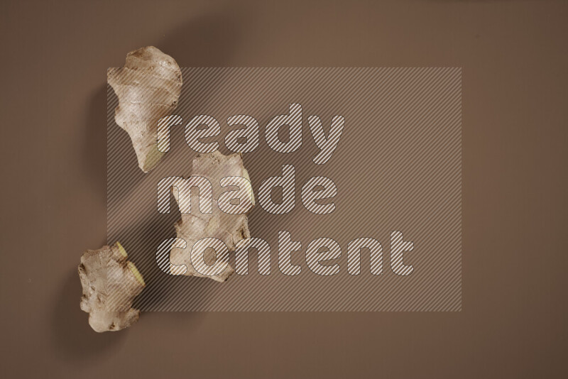 بهارات كاملة متنوعة تتضمن زنجبيل طازج ومجفف، أعواد قرفة، هيل، أصابع كركم، قرنفل، يانسون نجمي على خلفية بيج