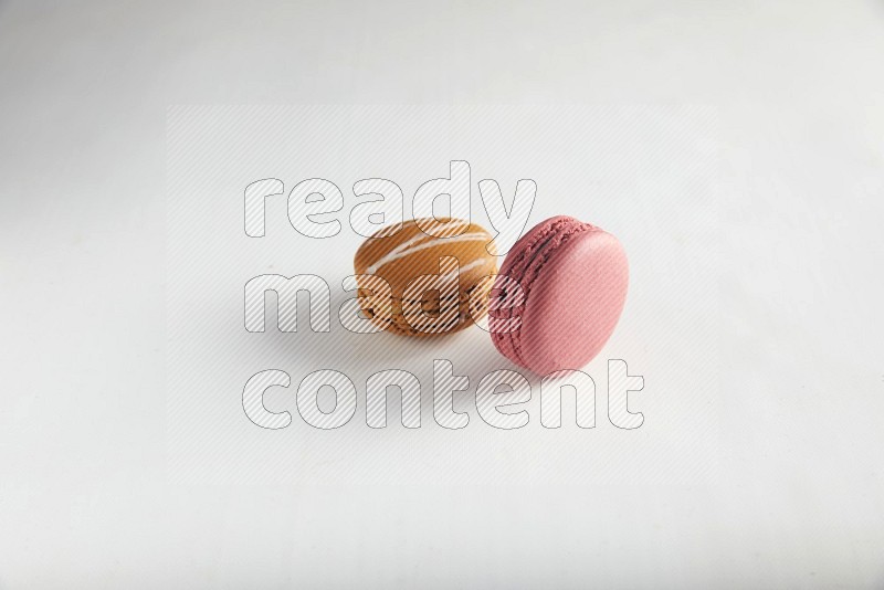 45º Shot of of two assorted Brown Irish Cream, and Pink Raspberry macarons on white background