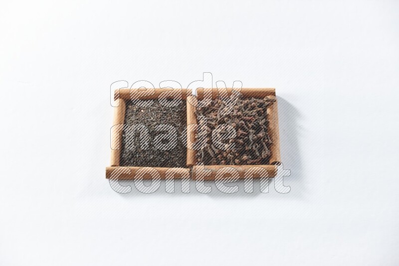 مربعان من أعواد القرفة ممتلئان بالشاي الأسود وحبوب القرنفل علي خلفية بيضاء