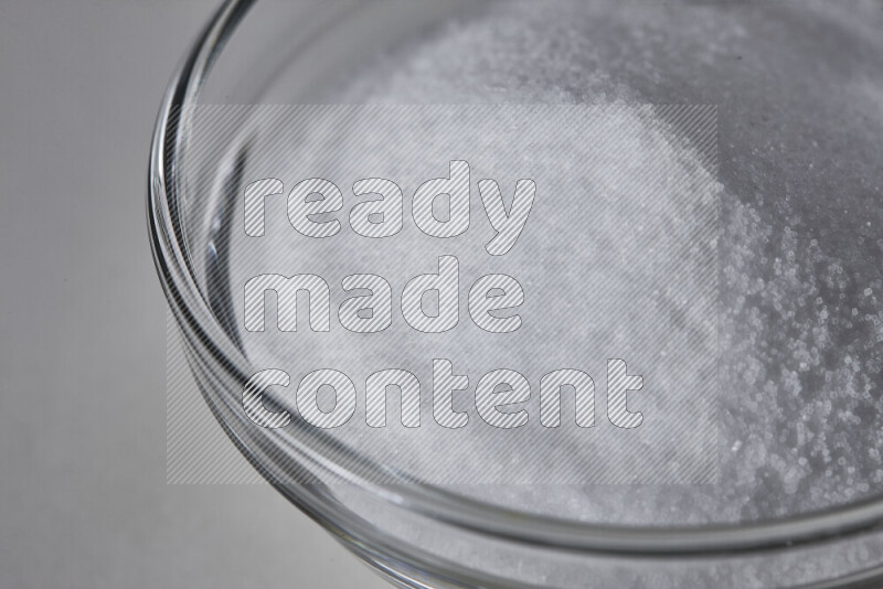 A glass bowl full of fine table salt on white background