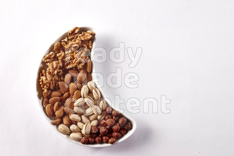 Mixed nuts in a crescent pottery plate on white background