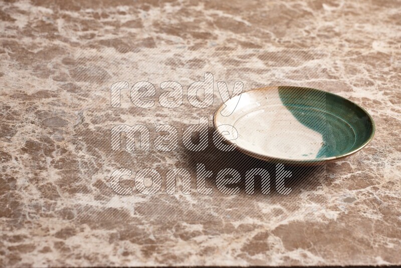 A multicolored pottery plate on beige marble background