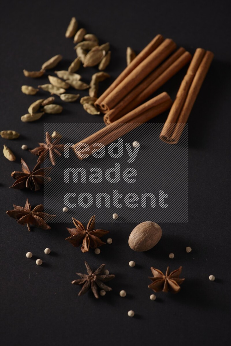Cinnamon sticks, cardamom, star anise, nutmeg and white peppers on a black background