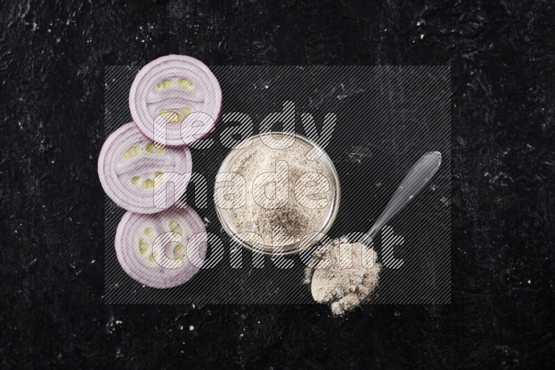 A glass jar full of onion powder on black background