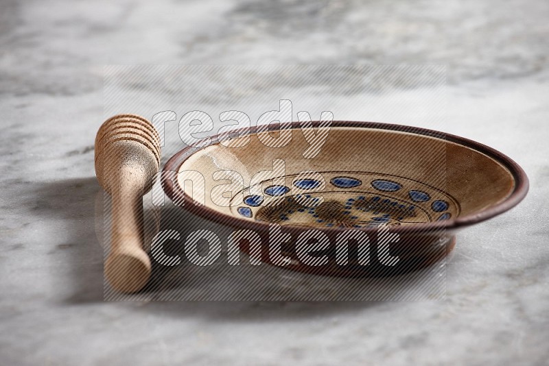 Decorative Pottery Plate with wooden honey handle on the side with grey marble flooring, 15 degree angle
