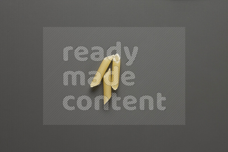 Mini penne pasta on grey background