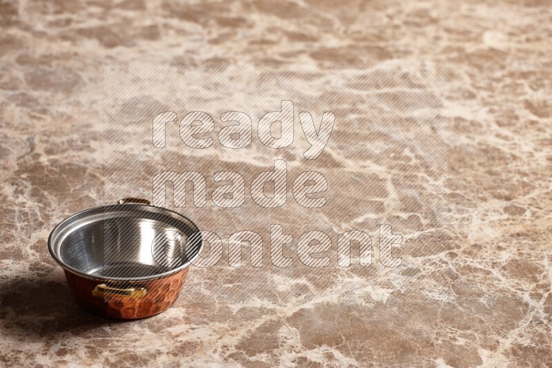 A small copper pot on beige marble background