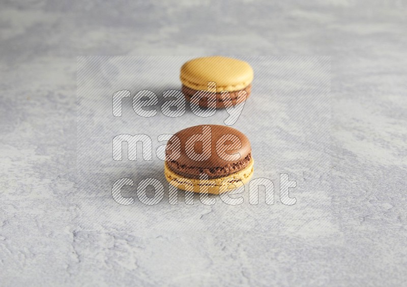 45º Shot of two Yellow and Brown Chai Latte macarons r on white  marble background