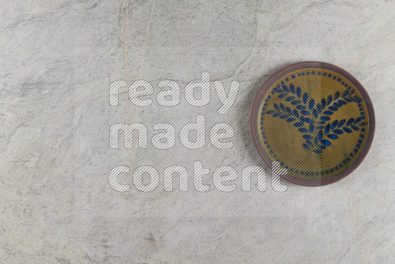 A decorative pottery plate on grey marble background