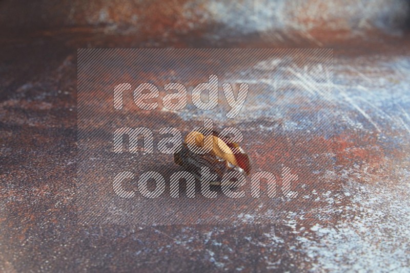 one almond stuffed madjoul date on a rustic reddish background