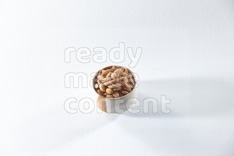A beige ceramic bowl full of peeled almonds on a white background in different angles