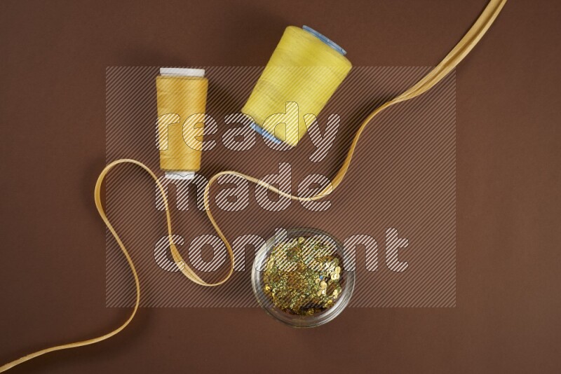 مجموعة من أدوات الخياطة والتفصيل صفراء اللون على خلفية بنية