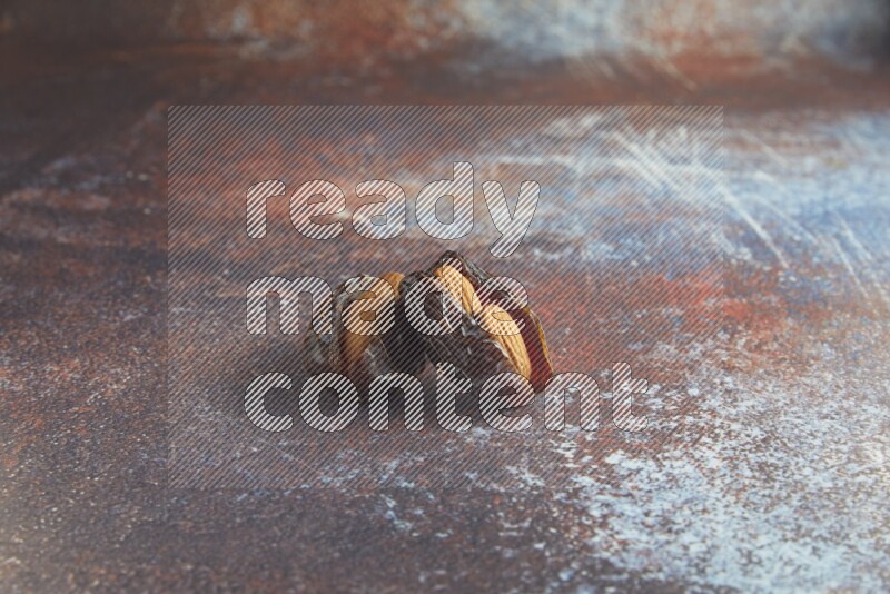 two almond stuffed madjoul dates on a rustic reddish background
