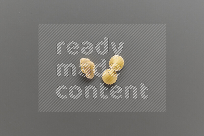 Snails pasta with other types of pasta on grey background