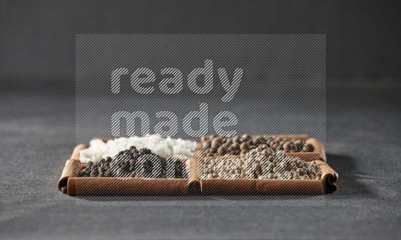 4 squares of cinnamon sticks full of black pepper, white pepper, allspice and white salt on black flooring